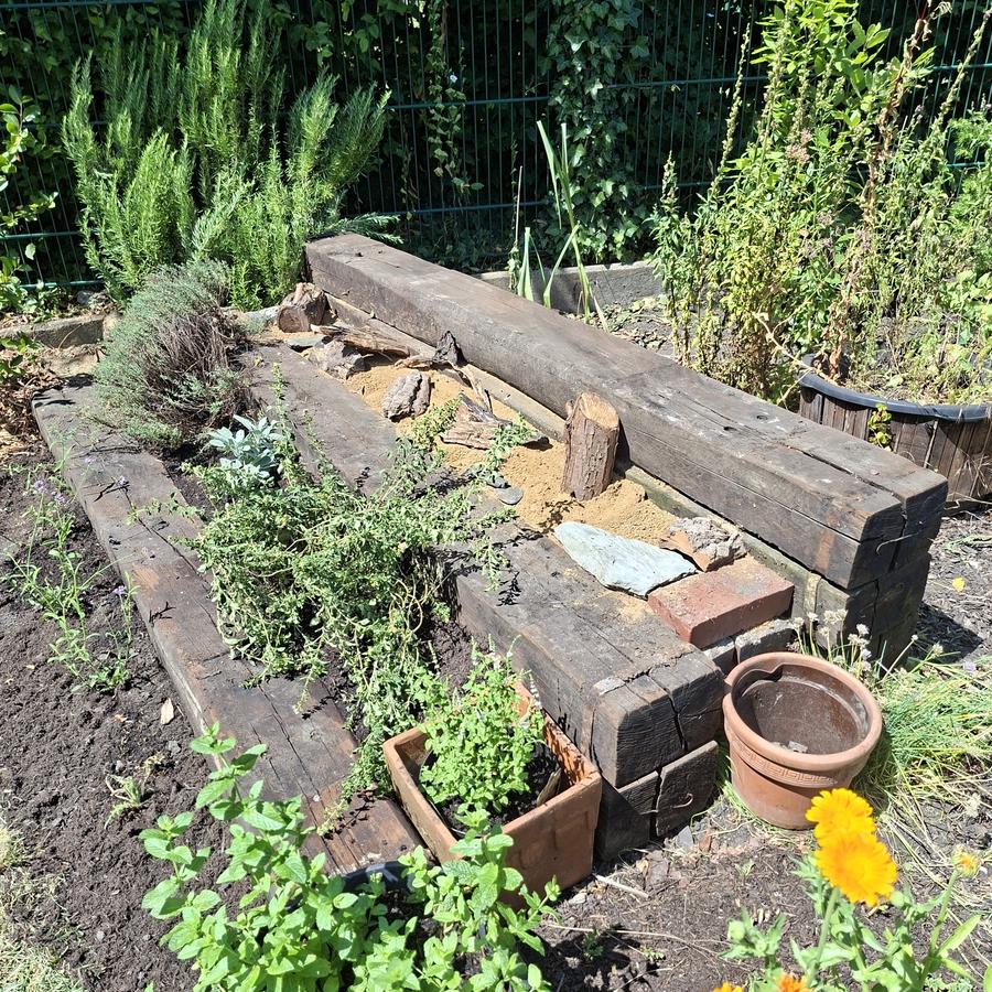 Ein Sandarium, gebaut aus alten Bahnschwellen in Treppenform. Die untere Ebene fungiert als Kräutergarten, die obere Ebene ist mit Sand und Lehm für Schmetterlinge ausgelegt.
