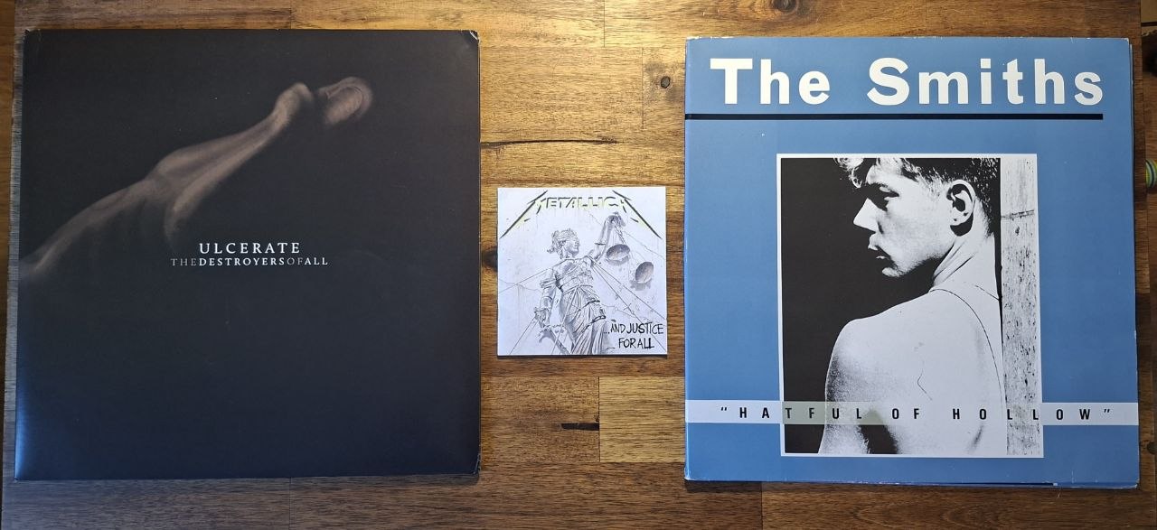 Ein Foto von drei Musik-Alben, der LP von Ulcerates ‘The Destroyers Of All’, der CD von Metallicas ‘…and justice for all’ und der LP von The Smiths ‘Hatful of Hollow’